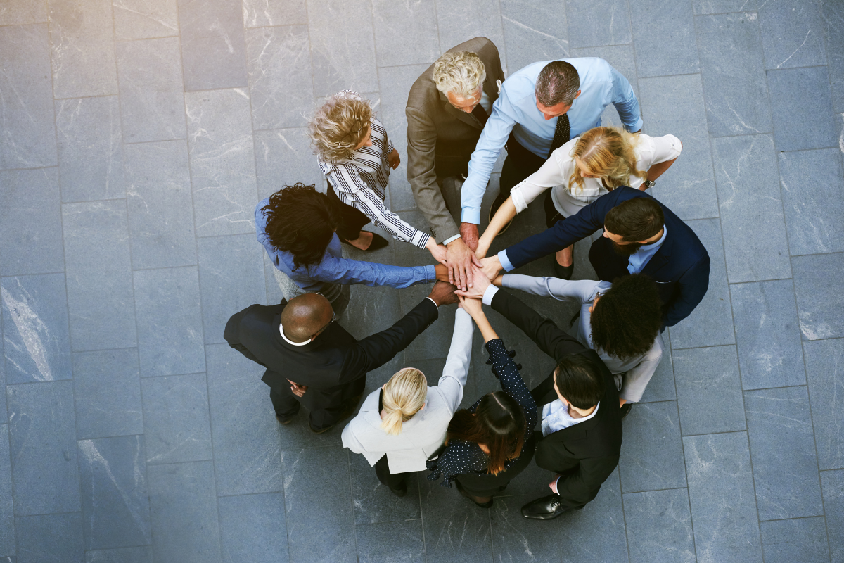 Workers in a huddle joining hands